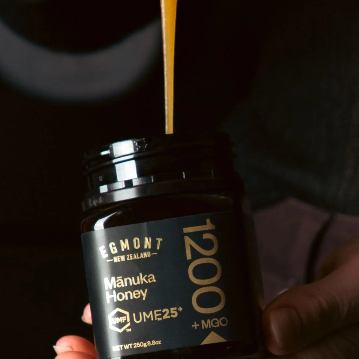 Man holding a jar of Māori Honey with honey dripping from a spoon