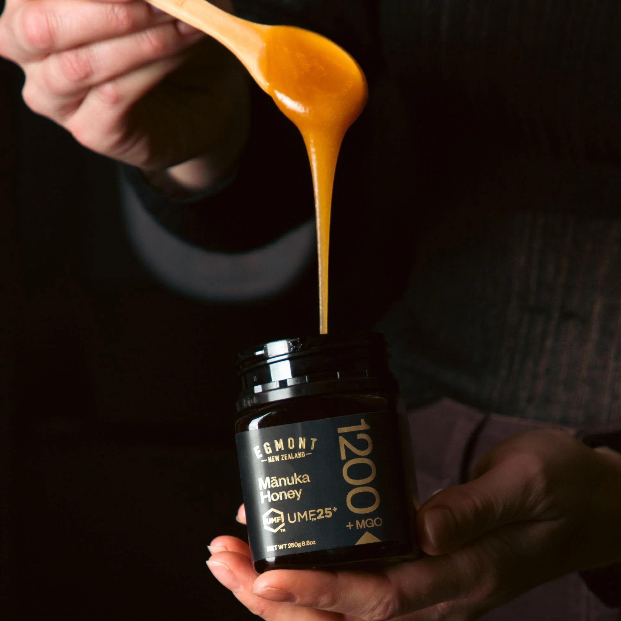 Man holding a jar of Māori Honey with honey dripping from a spoon